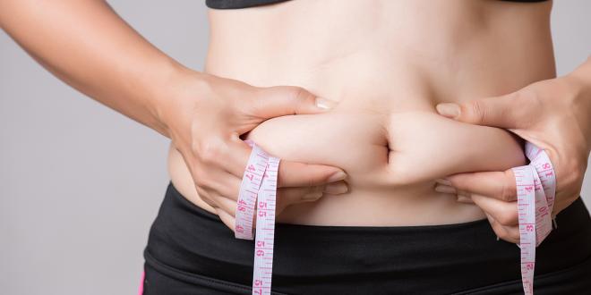 a healthy woman squeezing her excess tummy fat