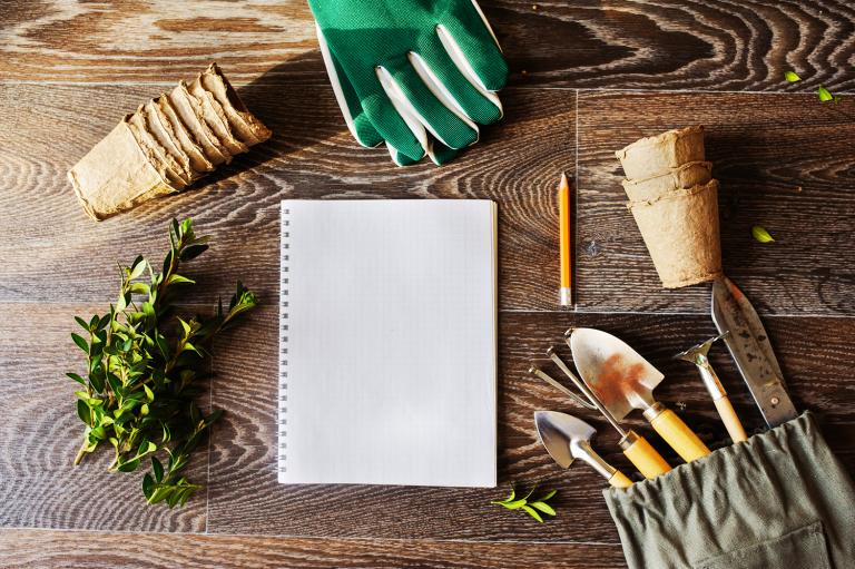 Note book, peat pots and tools laid out for spring garden planning. 