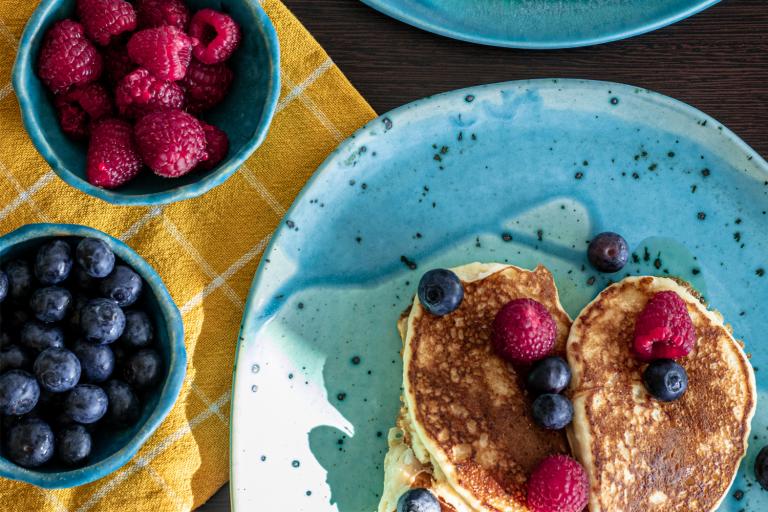 a plate of pancakes and bowls of berries